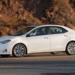 White 2017 Toyota Corolla parked on a paved road, showcasing its compact and modern design