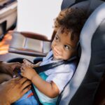 A parent securing a child in a car seat