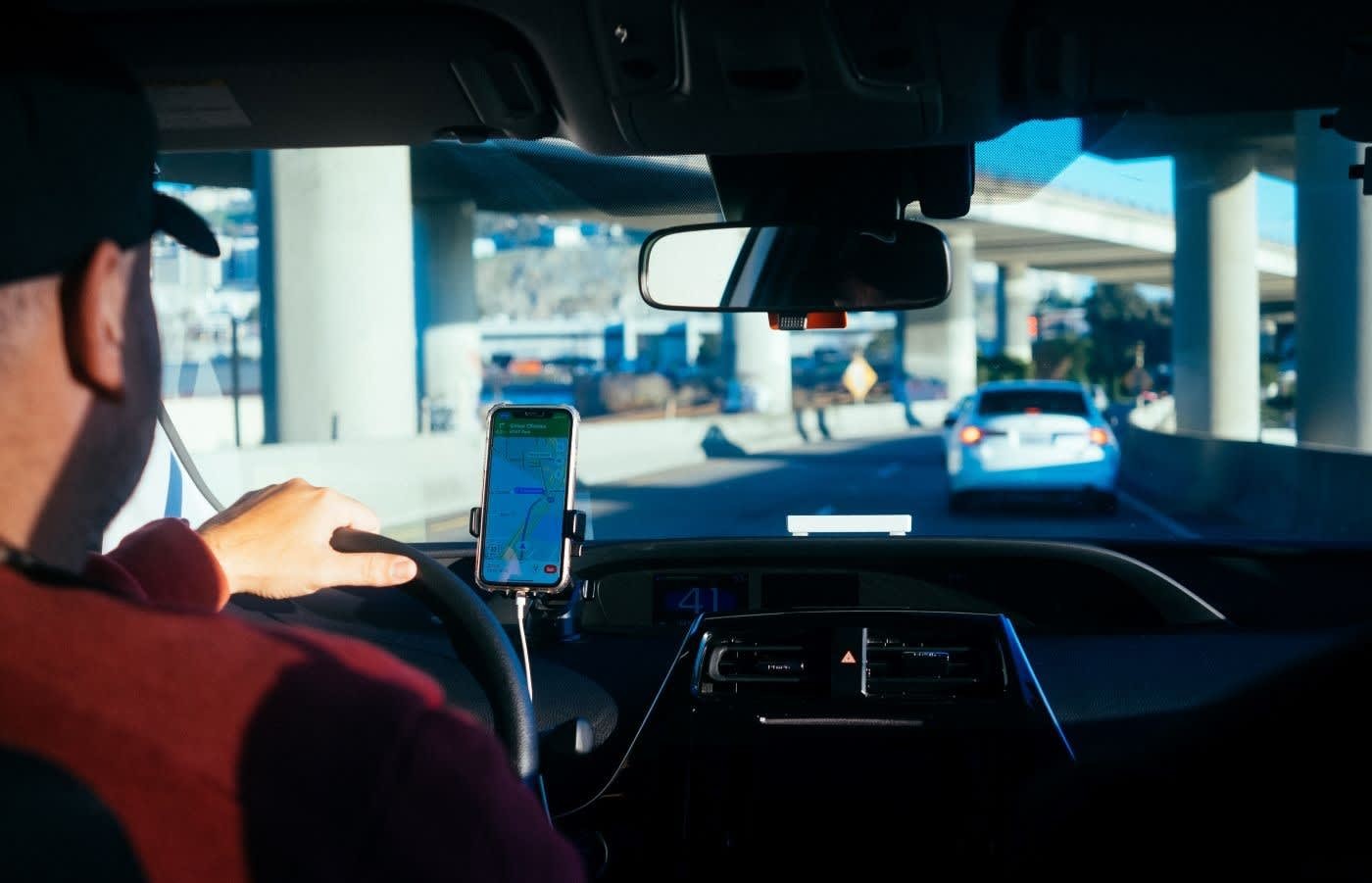 A person uses a smartphone for car navigation while driving a Zipcar.