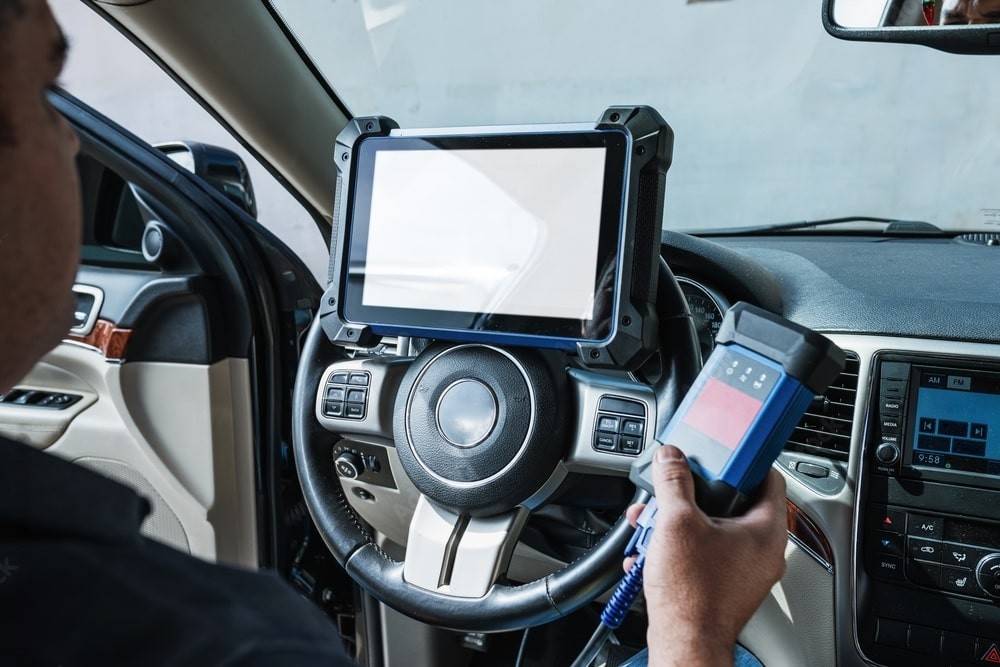 Professional technicians programming a car computer using diagnostic tools at an automotive service center