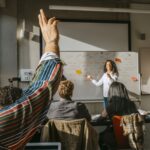 Student raising hand in a college classroom