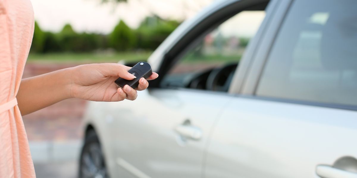 Hands holding a car key fob and car keys, suggesting DIY programming attempt