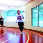 Senior woman using a treadmill with guidance from a fitness instructor, emphasizing personalized exercise plans and health monitoring.