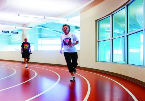 Senior woman using a treadmill with guidance from a fitness instructor, emphasizing personalized exercise plans and health monitoring.