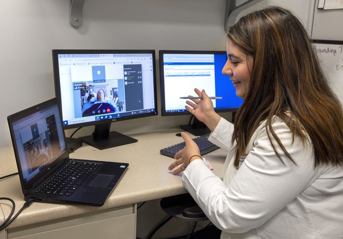 Dr. Kamia Thakur virtually visits with patient Mildred Shelly, gesturing and smiling on a video screen.