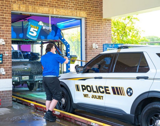 Police car entering Take 5 Car Wash for fleet program service