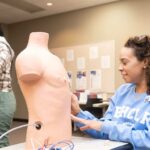 A group of patient care technician students in a classroom setting, learning practical skills, representing patient care technician programs near me.