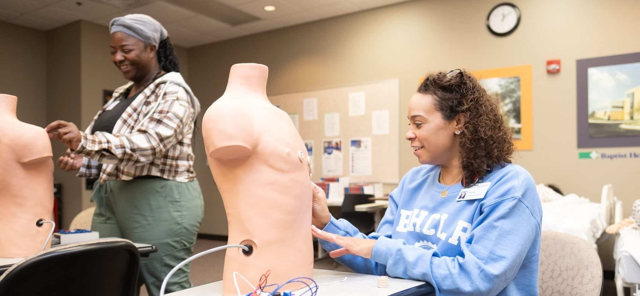 A group of patient care technician students in a classroom setting, learning practical skills, representing patient care technician programs near me.