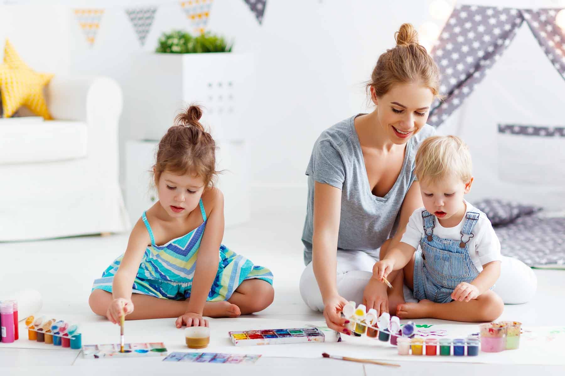 Babysitter working on arts and crafts with two young children.