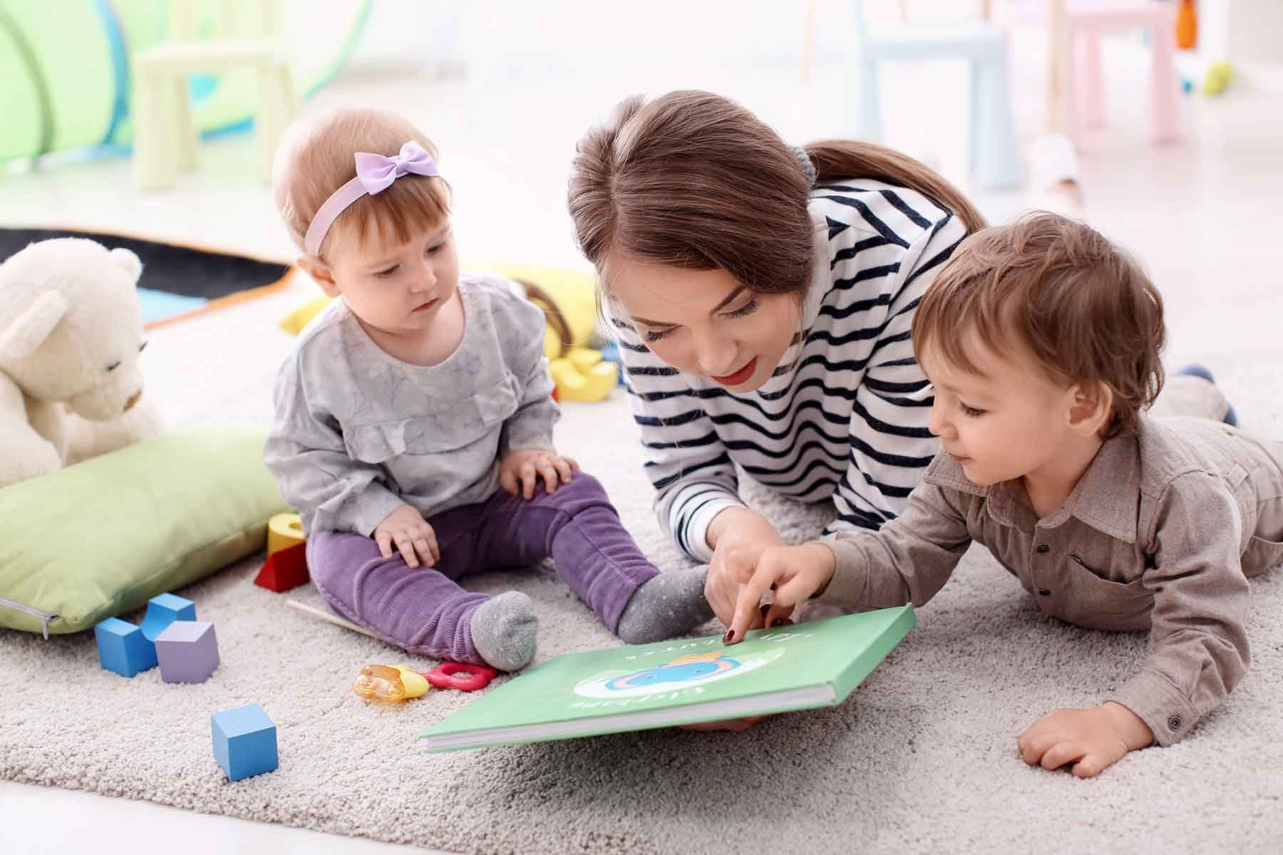 Nanny reading a book to two young children.