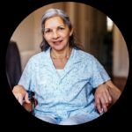 Mature woman with gray hair sitting in wheelchair smiles slightly